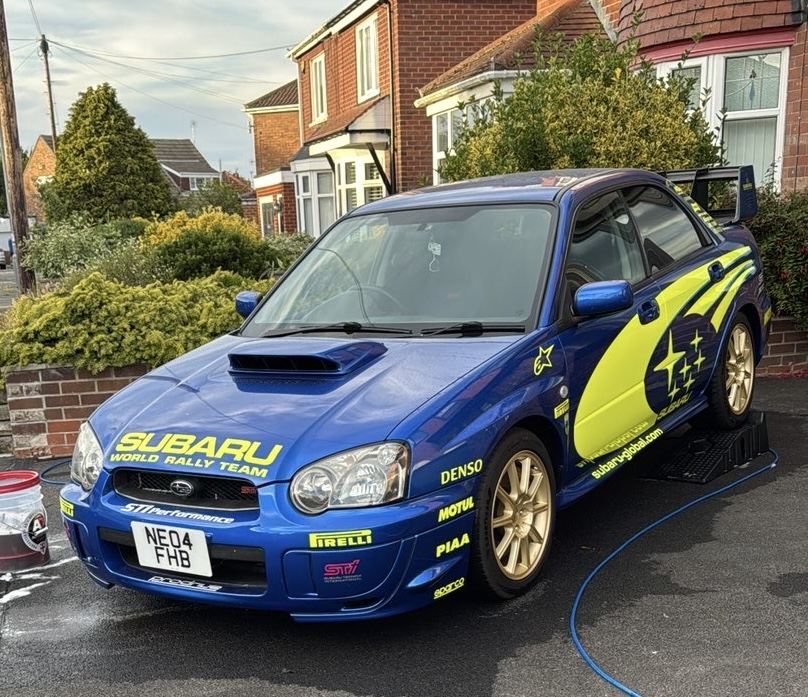 Front three-quarter view of the blue Subaru Impreza WRX STI after detailing, gleaming on a driveway