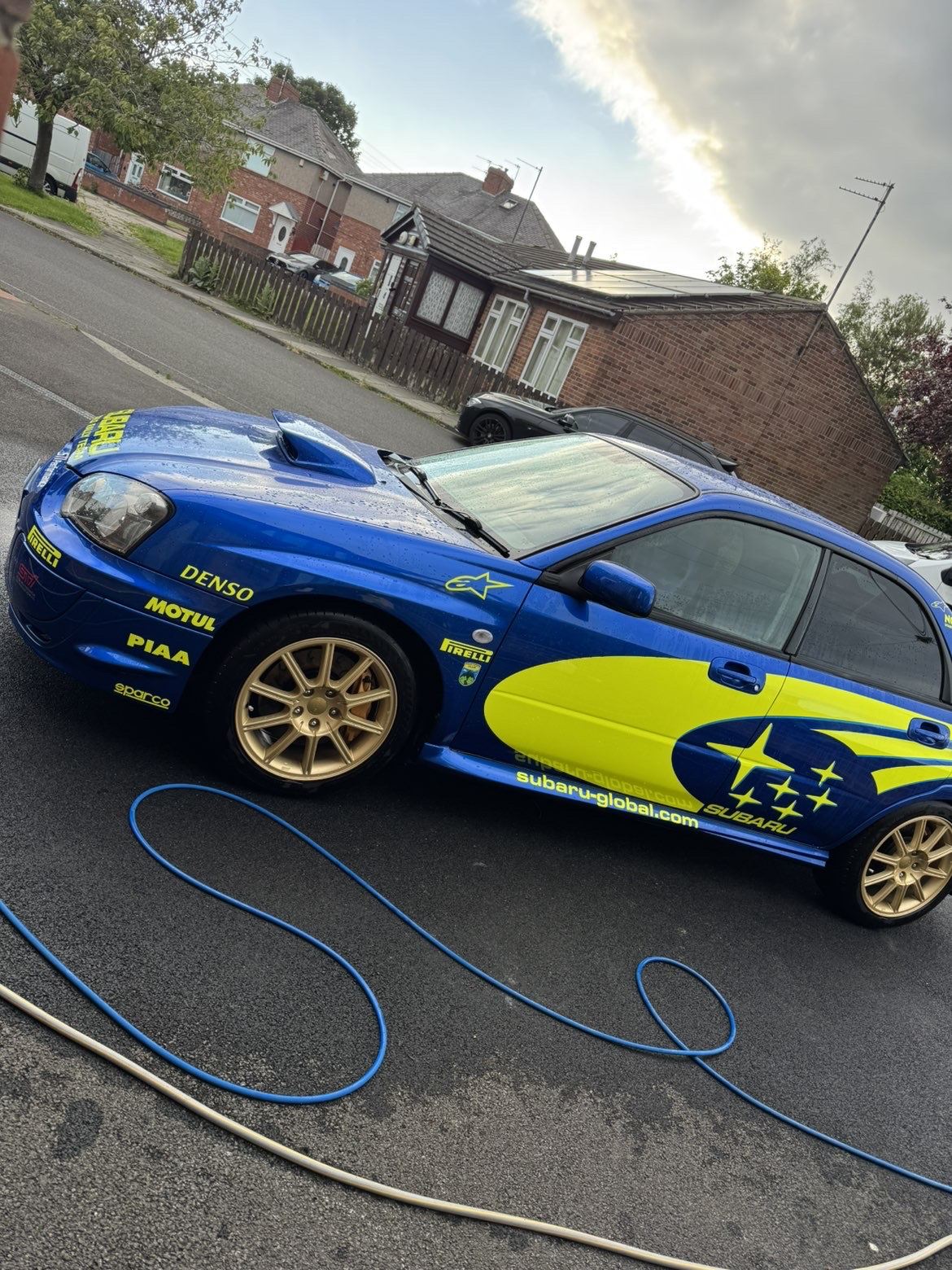 Side profile of the Subaru with gold alloy wheels, freshly washed
